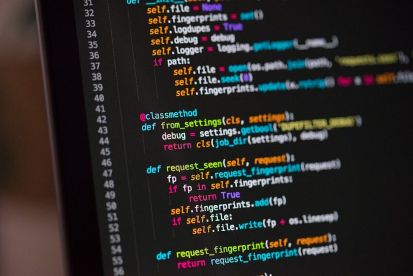 Dark laptop screen with glowing code in a dark room